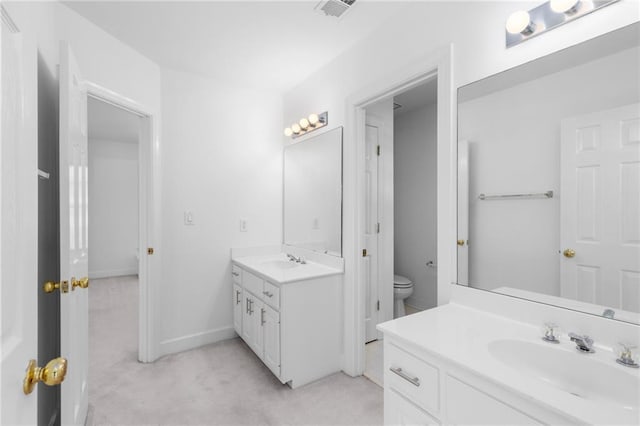 bathroom with toilet and dual bowl vanity