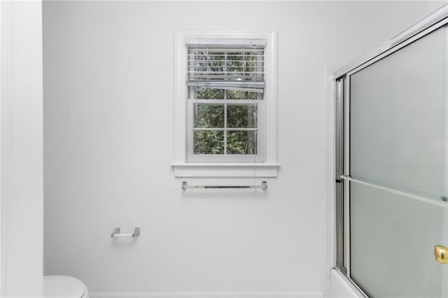 bathroom with shower / bath combination with glass door and toilet