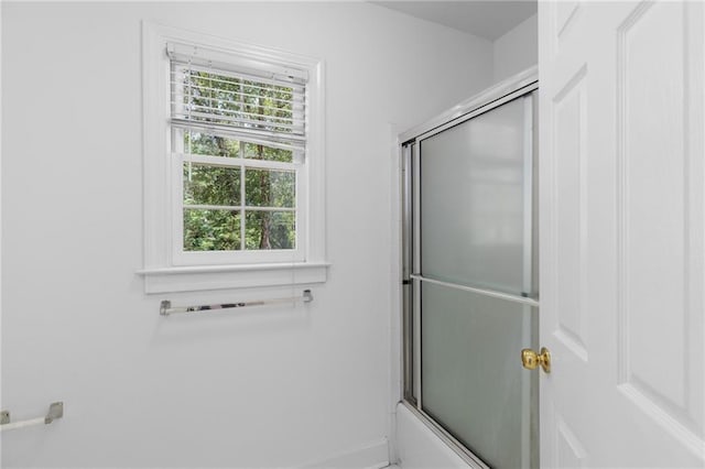 bathroom with bath / shower combo with glass door