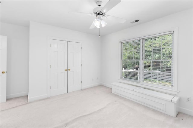 unfurnished bedroom featuring ceiling fan, a closet, and light carpet