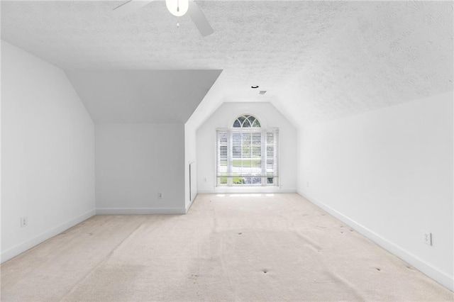 additional living space featuring a textured ceiling, vaulted ceiling, and light carpet
