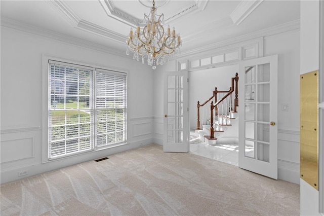 spare room with an inviting chandelier, ornamental molding, french doors, light carpet, and a tray ceiling