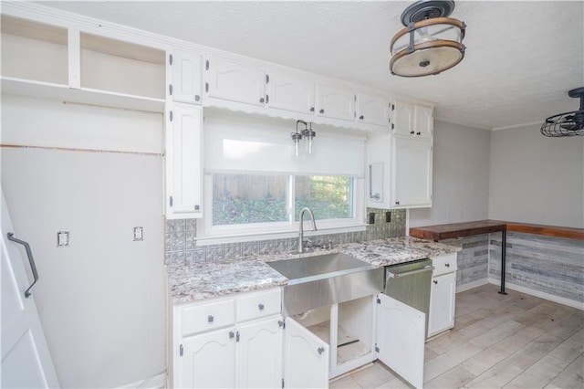 kitchen with light hardwood / wood-style floors, sink, light stone counters, and white cabinets