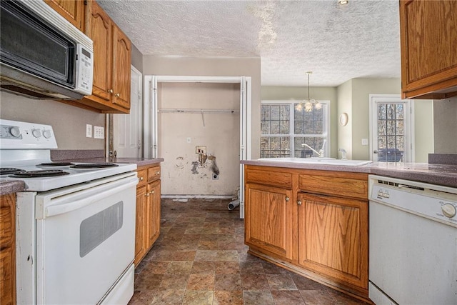 kitchen with pendant lighting, white appliances, an inviting chandelier, sink, and a textured ceiling