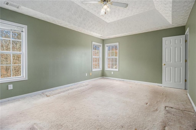 carpeted spare room featuring a tray ceiling, ceiling fan, and a textured ceiling