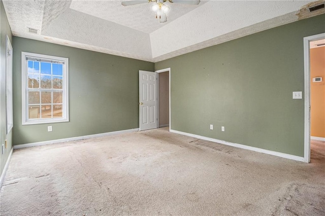 unfurnished room with carpet, a textured ceiling, a raised ceiling, and ceiling fan