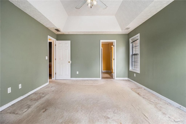 unfurnished bedroom with carpet, ceiling fan, a textured ceiling, and a tray ceiling