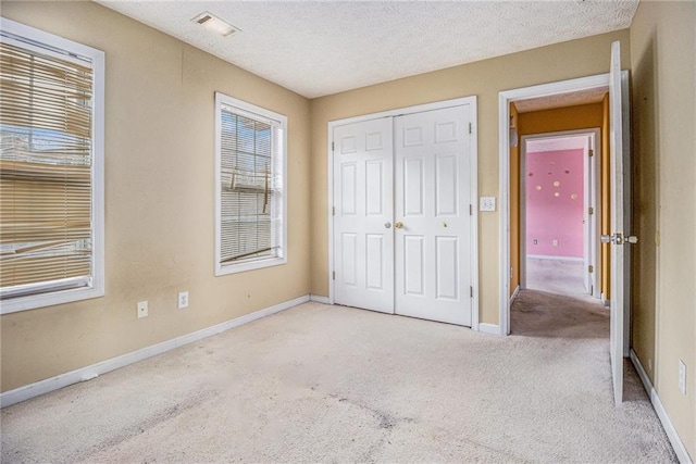 unfurnished bedroom with a closet, light colored carpet, and a textured ceiling