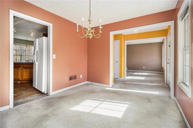 carpeted empty room featuring a notable chandelier