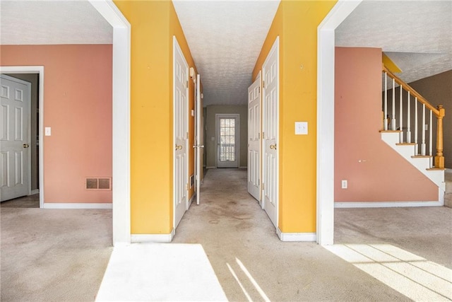 hall featuring a textured ceiling and light carpet