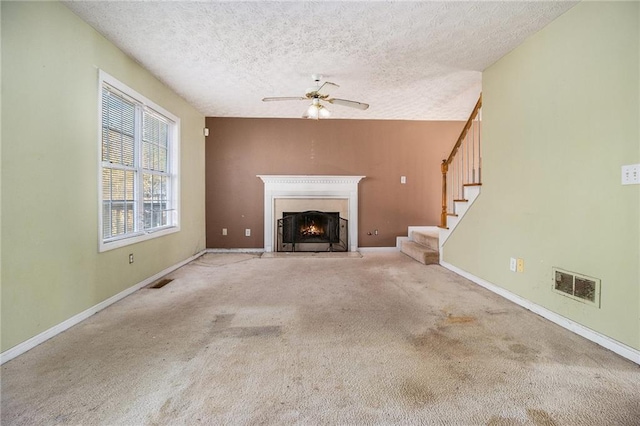 unfurnished living room with carpet flooring, a textured ceiling, and ceiling fan