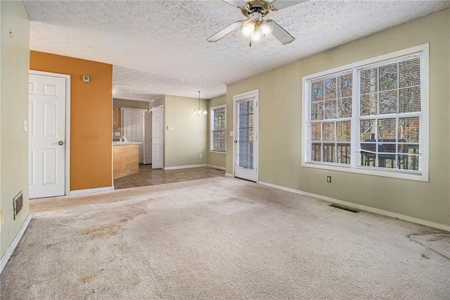 interior space featuring ceiling fan with notable chandelier, carpet floors, and a textured ceiling