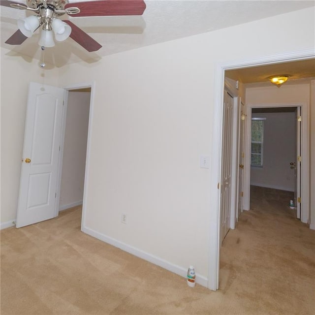 spare room with ceiling fan and light colored carpet