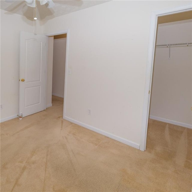 unfurnished bedroom featuring light carpet, ceiling fan, and a closet