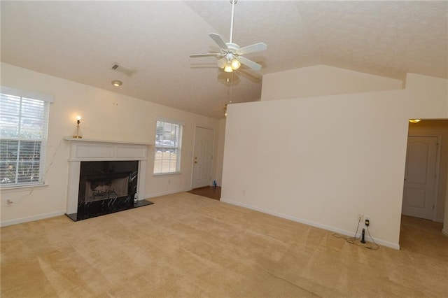 unfurnished living room featuring a healthy amount of sunlight, lofted ceiling, and light carpet