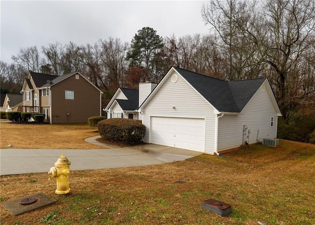 view of side of property featuring a garage, a yard, and central air condition unit