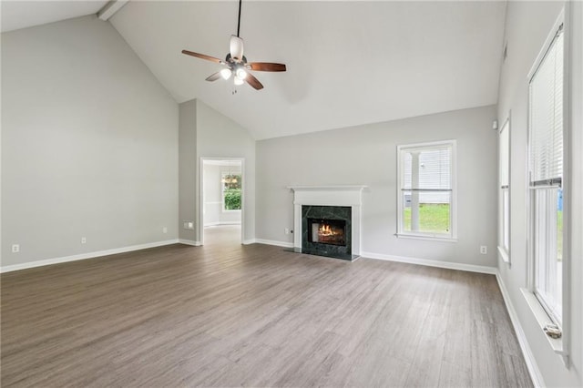 unfurnished living room featuring plenty of natural light, high vaulted ceiling, ceiling fan, and wood finished floors