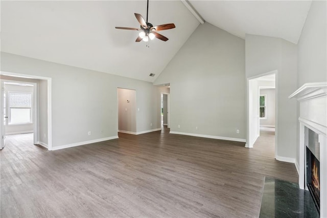 unfurnished living room featuring ceiling fan, a fireplace, wood finished floors, high vaulted ceiling, and baseboards