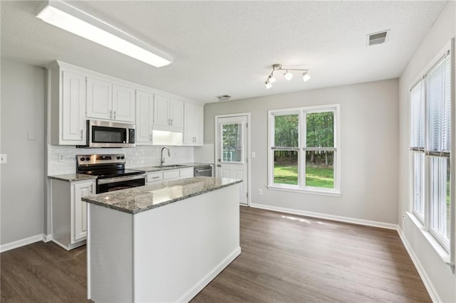 kitchen with visible vents, dark wood finished floors, a sink, white cabinets, and stainless steel appliances