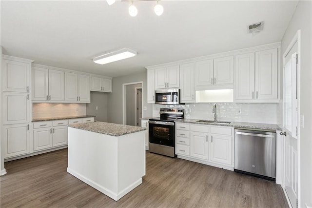kitchen with a sink, white cabinets, stainless steel appliances, and wood finished floors