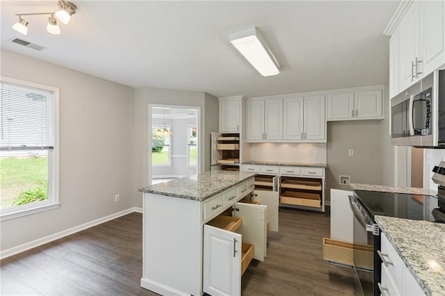 kitchen with visible vents, stainless steel microwave, range with electric cooktop, and a healthy amount of sunlight