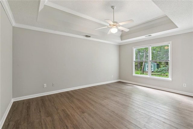 empty room featuring visible vents, ceiling fan, wood finished floors, and a tray ceiling
