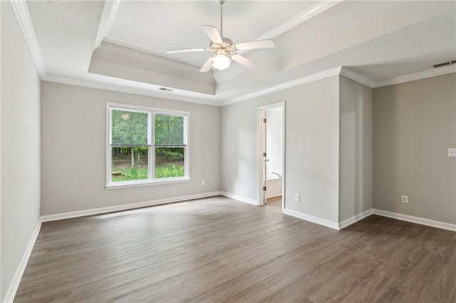 unfurnished room with crown molding, visible vents, wood finished floors, a raised ceiling, and a ceiling fan