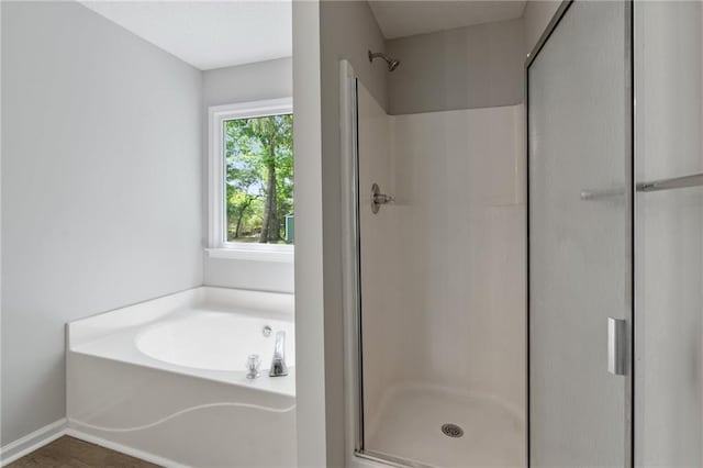 full bath featuring baseboards, a stall shower, a garden tub, and wood finished floors