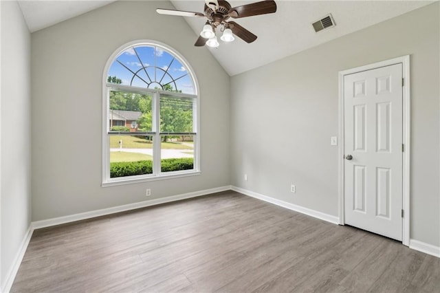 spare room with visible vents, lofted ceiling, wood finished floors, baseboards, and ceiling fan