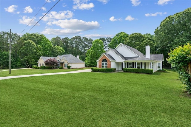 view of front facade featuring a front lawn, covered porch, a chimney, and concrete driveway