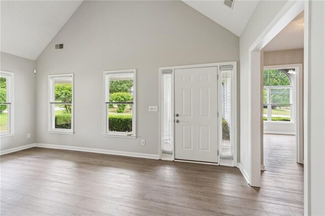 entrance foyer featuring baseboards, wood finished floors, visible vents, and high vaulted ceiling