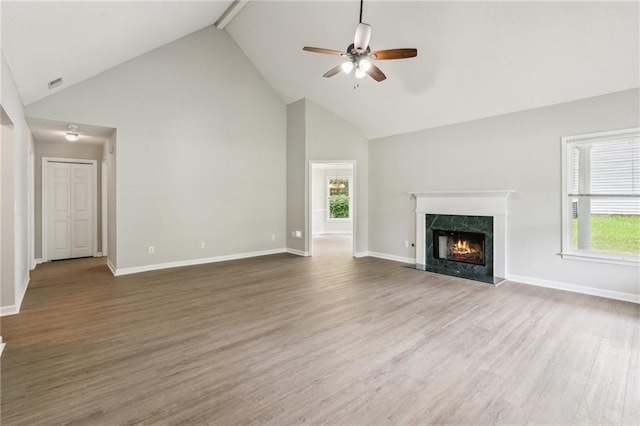 unfurnished living room featuring high vaulted ceiling, a healthy amount of sunlight, ceiling fan, and a high end fireplace