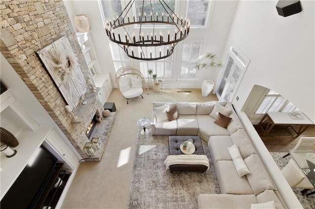 living room with a fireplace, a towering ceiling, a healthy amount of sunlight, and an inviting chandelier