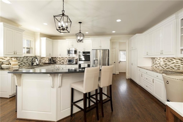 kitchen with appliances with stainless steel finishes, white cabinetry, and a kitchen island