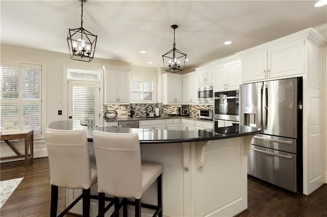 kitchen featuring white cabinets, appliances with stainless steel finishes, hanging light fixtures, and sink