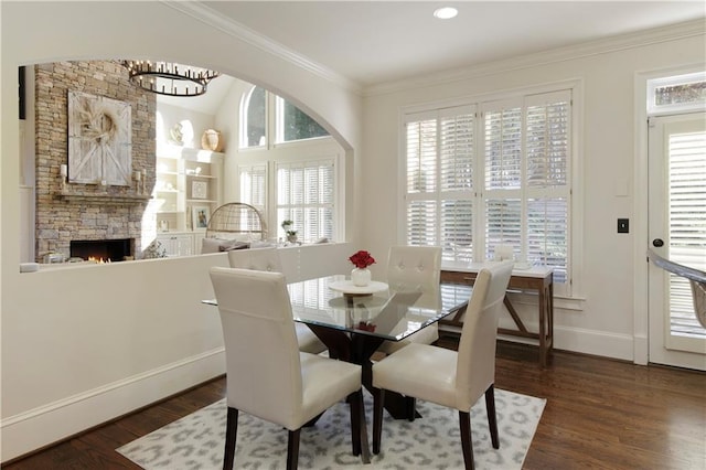 dining room featuring a fireplace, dark wood-type flooring, a healthy amount of sunlight, and a notable chandelier