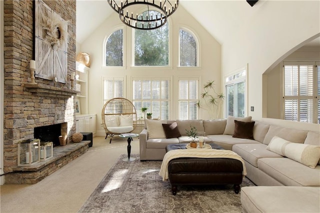 living room featuring high vaulted ceiling, a fireplace, a wealth of natural light, carpet floors, and a chandelier