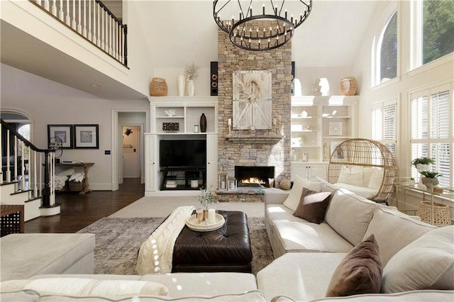 living room with a fireplace, a high ceiling, dark hardwood / wood-style floors, and an inviting chandelier