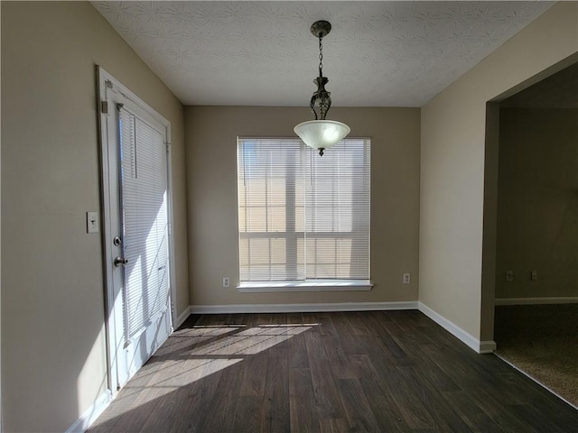 unfurnished dining area featuring a textured ceiling and dark wood-type flooring