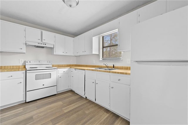 kitchen with white appliances, light wood finished floors, light countertops, under cabinet range hood, and a sink