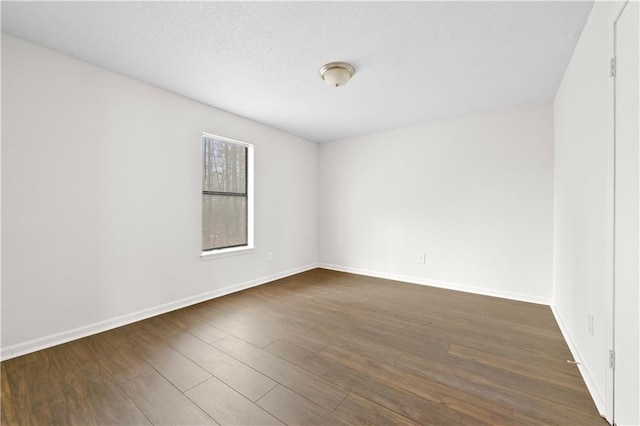 unfurnished room with a textured ceiling, dark wood-type flooring, and baseboards