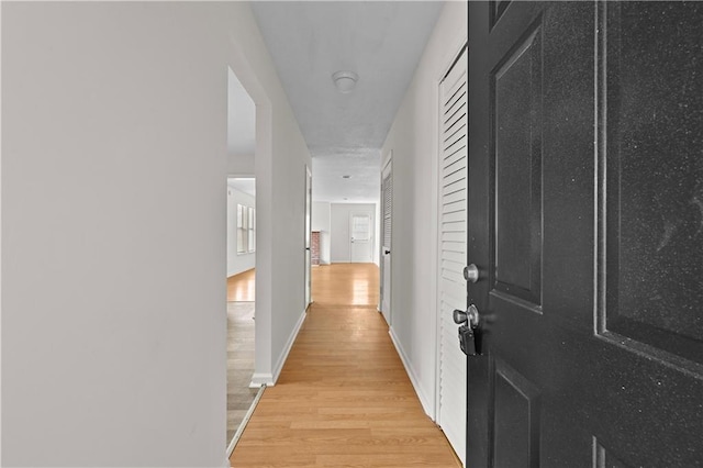 corridor with light wood-style floors and baseboards