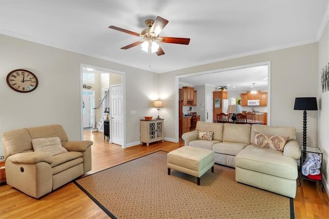 living room with light wood-style floors, a ceiling fan, and ornamental molding