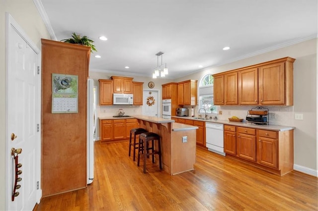 kitchen with a breakfast bar, a sink, white appliances, light countertops, and decorative backsplash