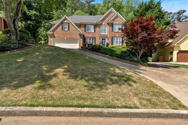 colonial inspired home with brick siding, an attached garage, a front yard, and aphalt driveway