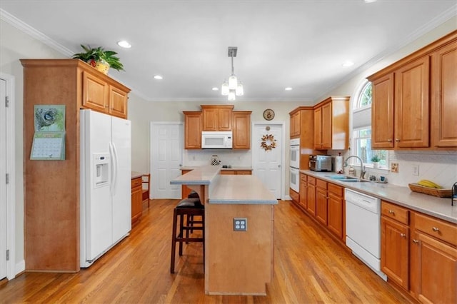 kitchen with white appliances, a kitchen breakfast bar, light wood-type flooring, a sink, and backsplash