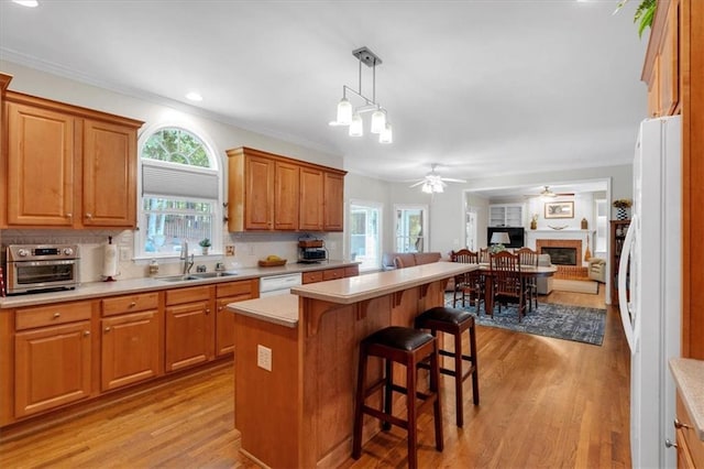 kitchen with white appliances, open floor plan, a sink, light wood finished floors, and a wealth of natural light