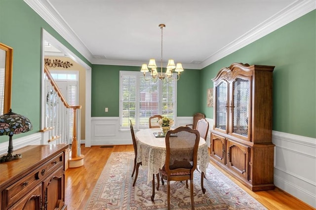 dining room featuring an inviting chandelier, wainscoting, and light wood finished floors