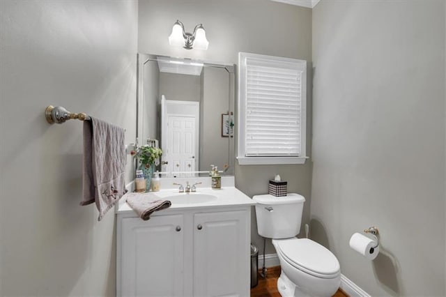 half bath with toilet, baseboards, wood finished floors, and vanity