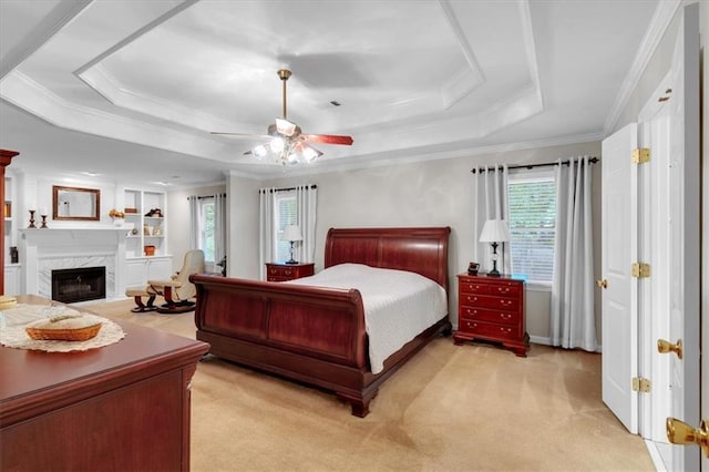 bedroom with crown molding, a raised ceiling, a fireplace, and light colored carpet